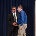 Doctor Smart shaking hands with an award recipient in a blue shirt